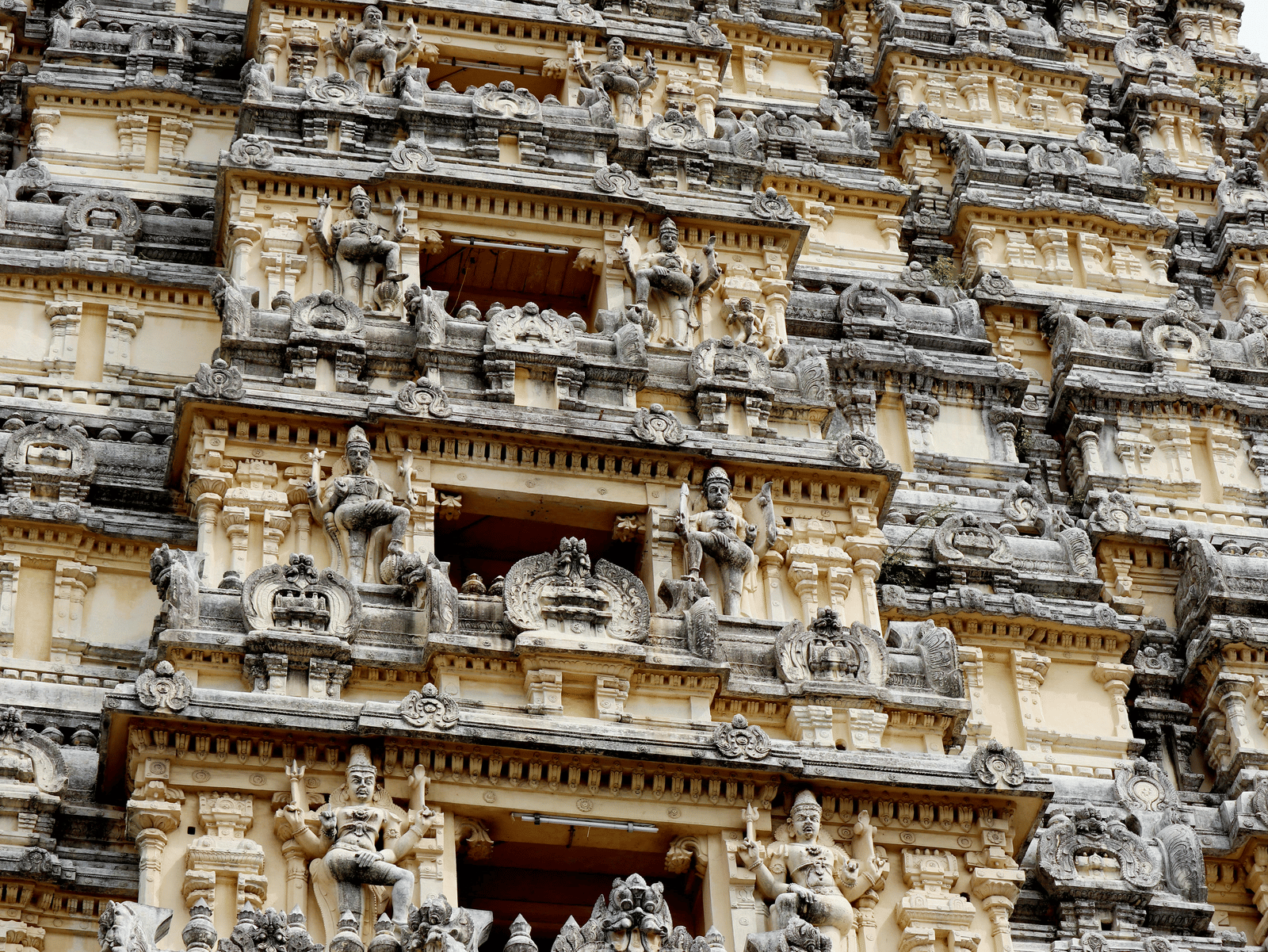 Close-up of intricately carved stone sculptures and detailed architectural elements on a South Indian temple tower (gopuram).