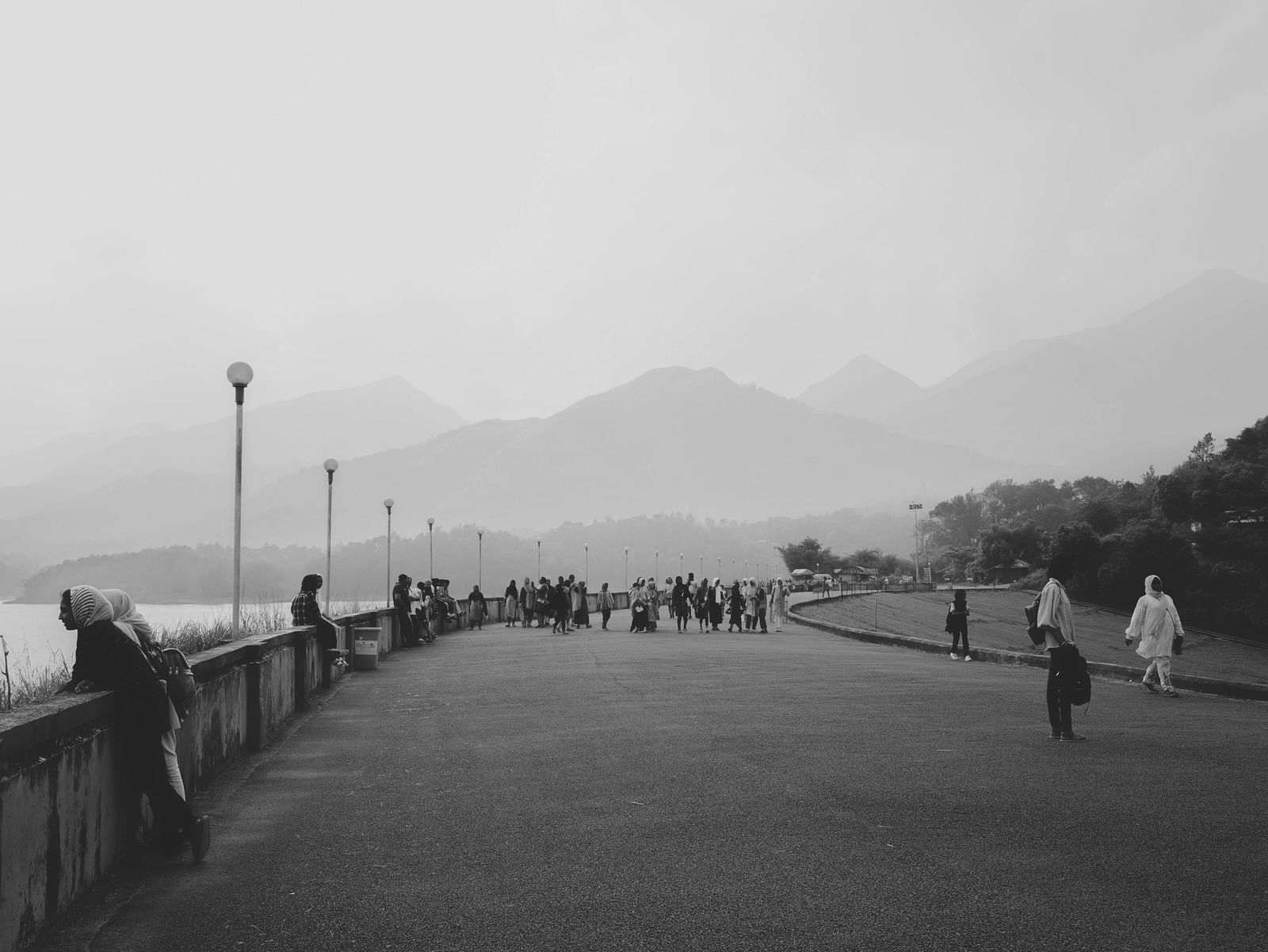 People walking along a foggy viewpoint with distant hills in the background.