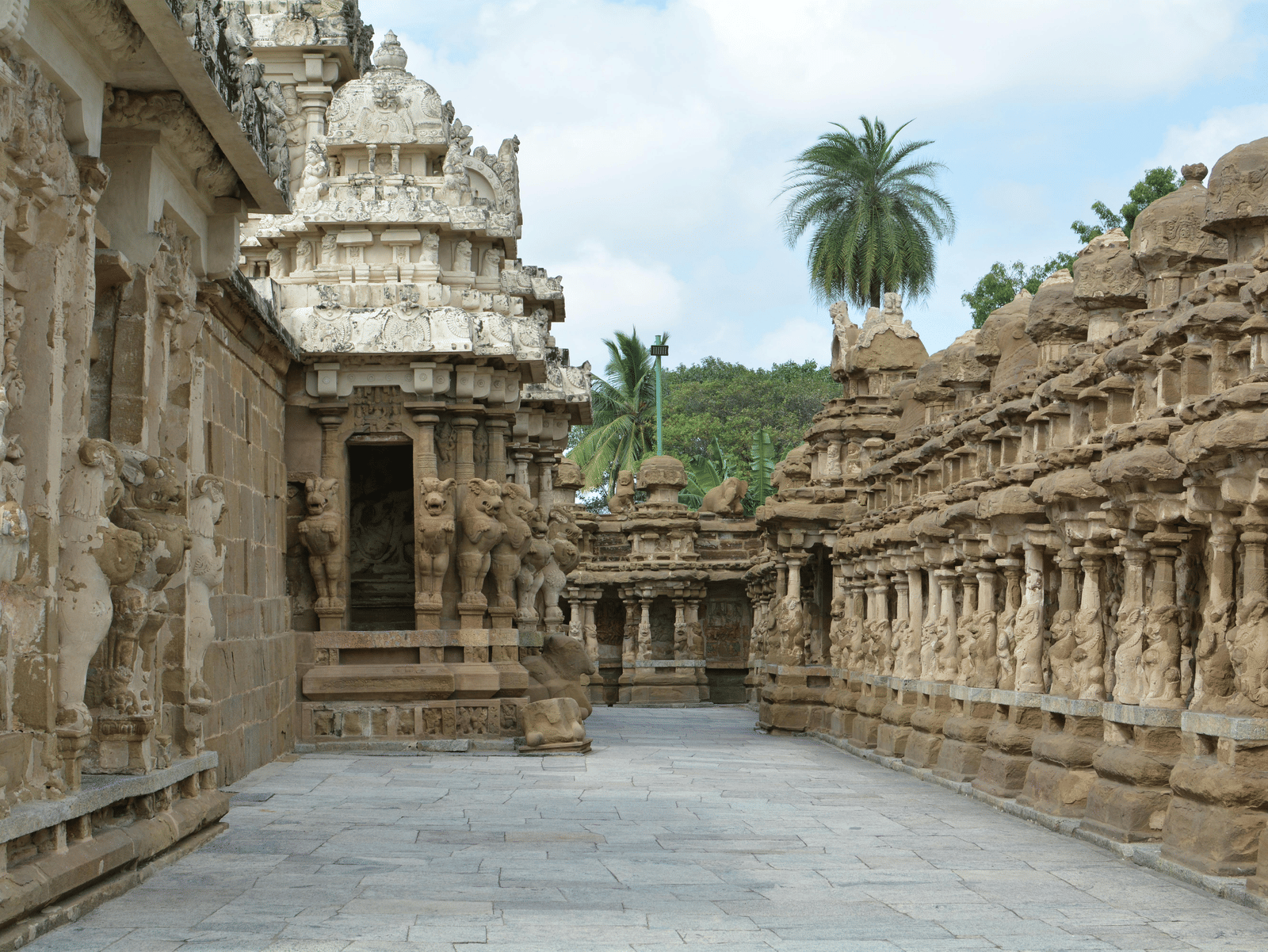 Narrow passage between two ornately carved stone walls of an ancient temple complex.