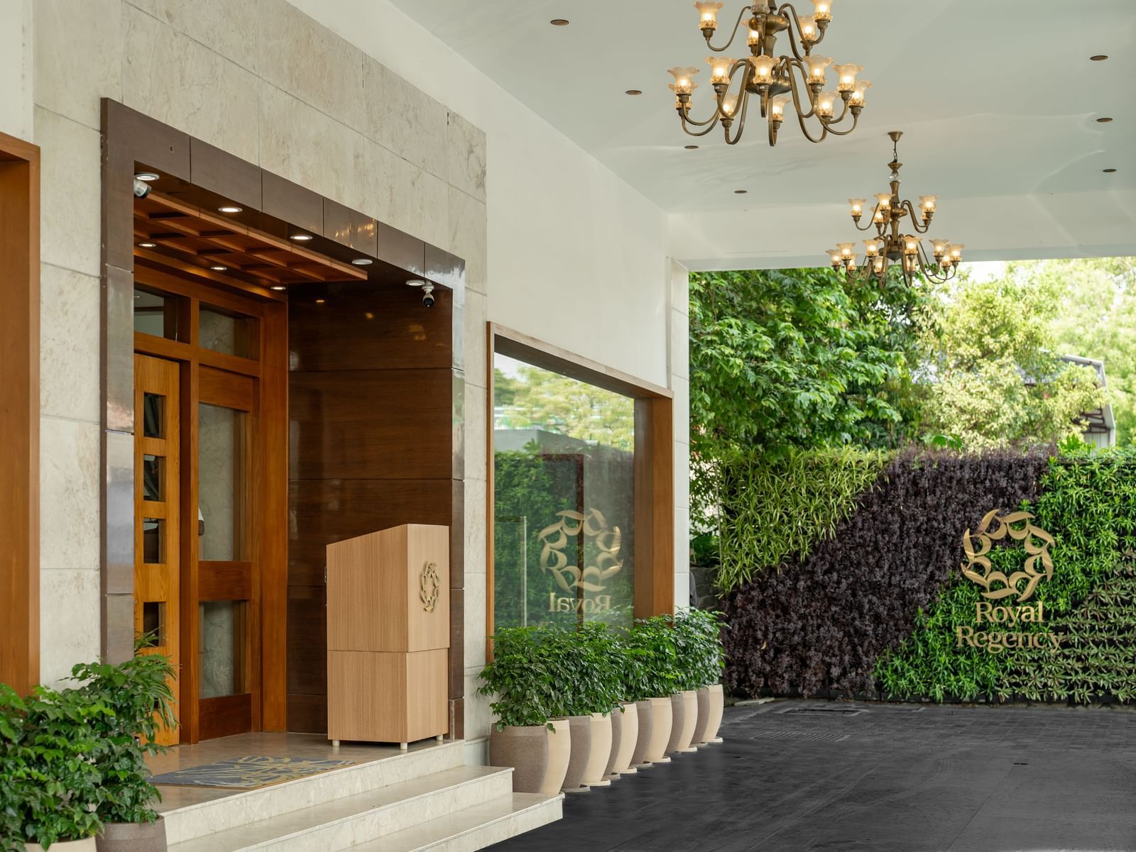 Hotel Royal Regency Chennai entrance with glass doors, greenery, and chandelier