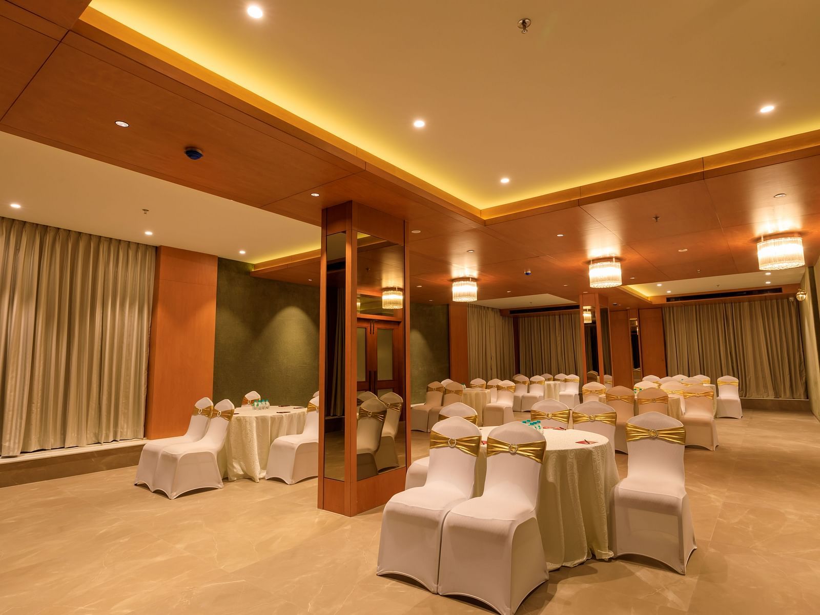 A softly lit function room at Lords Eco Inn Apple Gate is arranged with round tables and covered chairs, ready for an event.