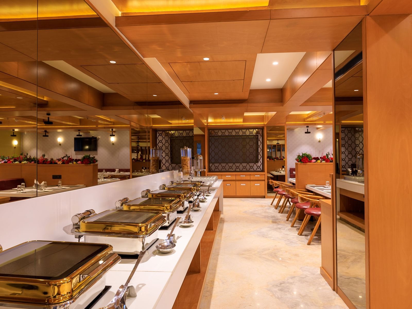 A brightly lit buffet area at Lords Eco Inn Apple Gate features multiple chafing dishes, ready to serve meals.