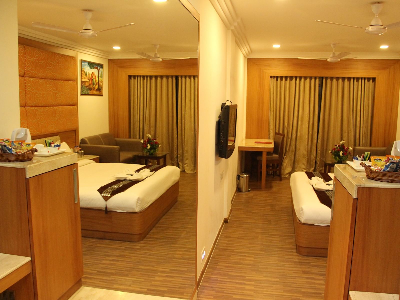 Spacious hotel room with sitting area and double bed, warmly lit