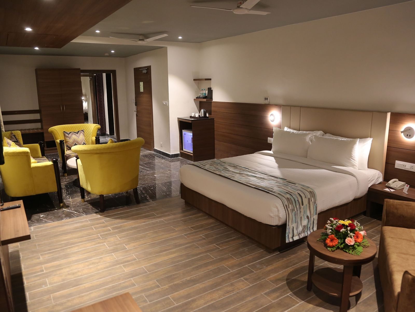 A well-appointed hotel room at Lords Inn Udaipur features a comfortable bed, a seating area with armchairs, and modern amenities.