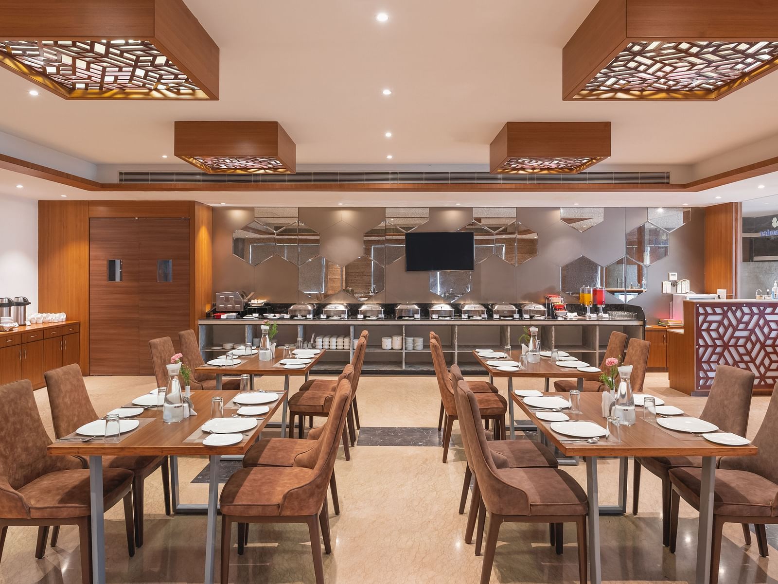 The spacious restaurant at Lords Inn Udaipur is set with multiple tables and chairs, featuring a buffet area in the background.