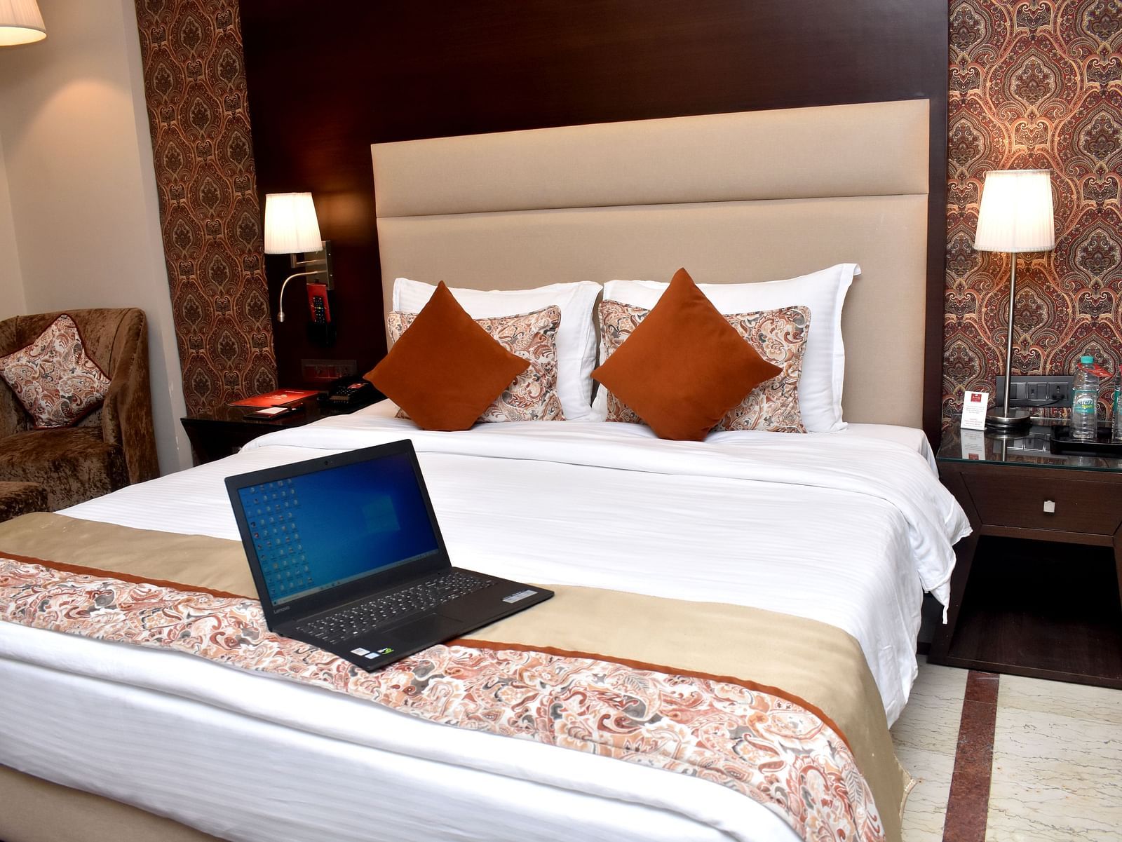 A modern hotel room with a bed, laptop, and warm lighting for a comfortable stay at Lords Plaza Surat.