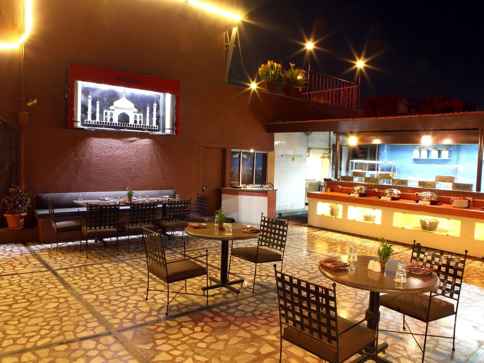 A warmly lit dining or lounge area with tables and chairs at Lords Plaza Surat.