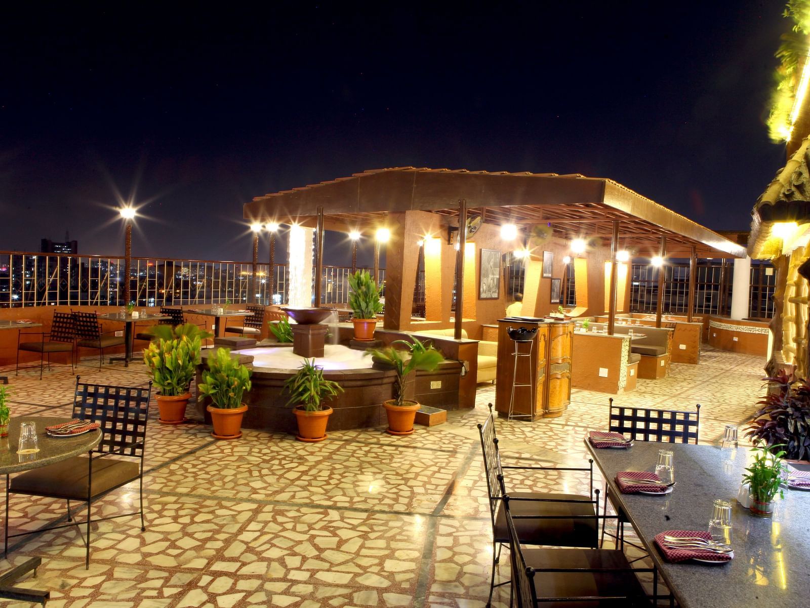 An outdoor seating area with covered structures at night at Lords Plaza Surat.