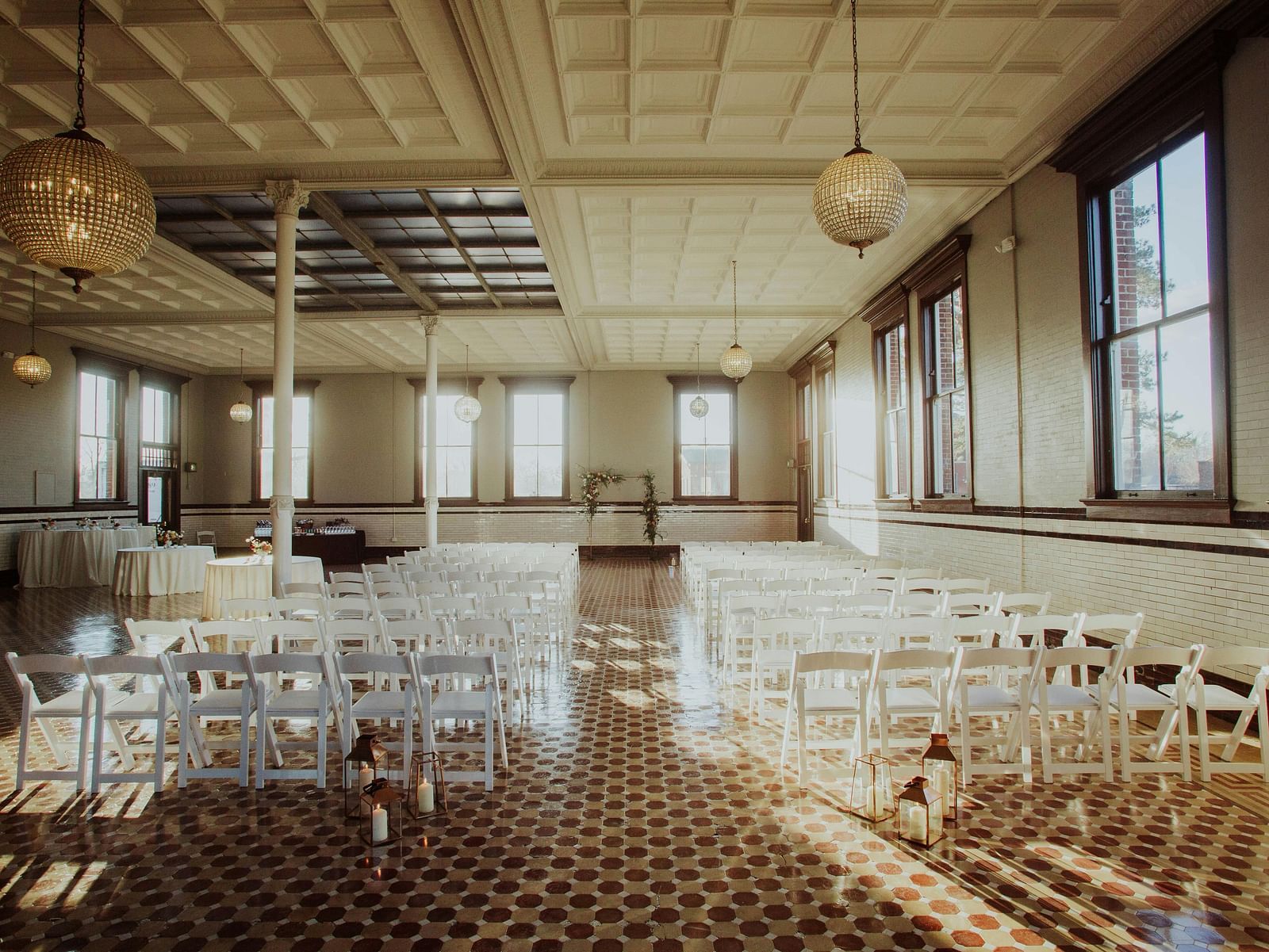A spacious, empty hall with rows of tables and chairs ready for an event at Lords Plaza Surat.