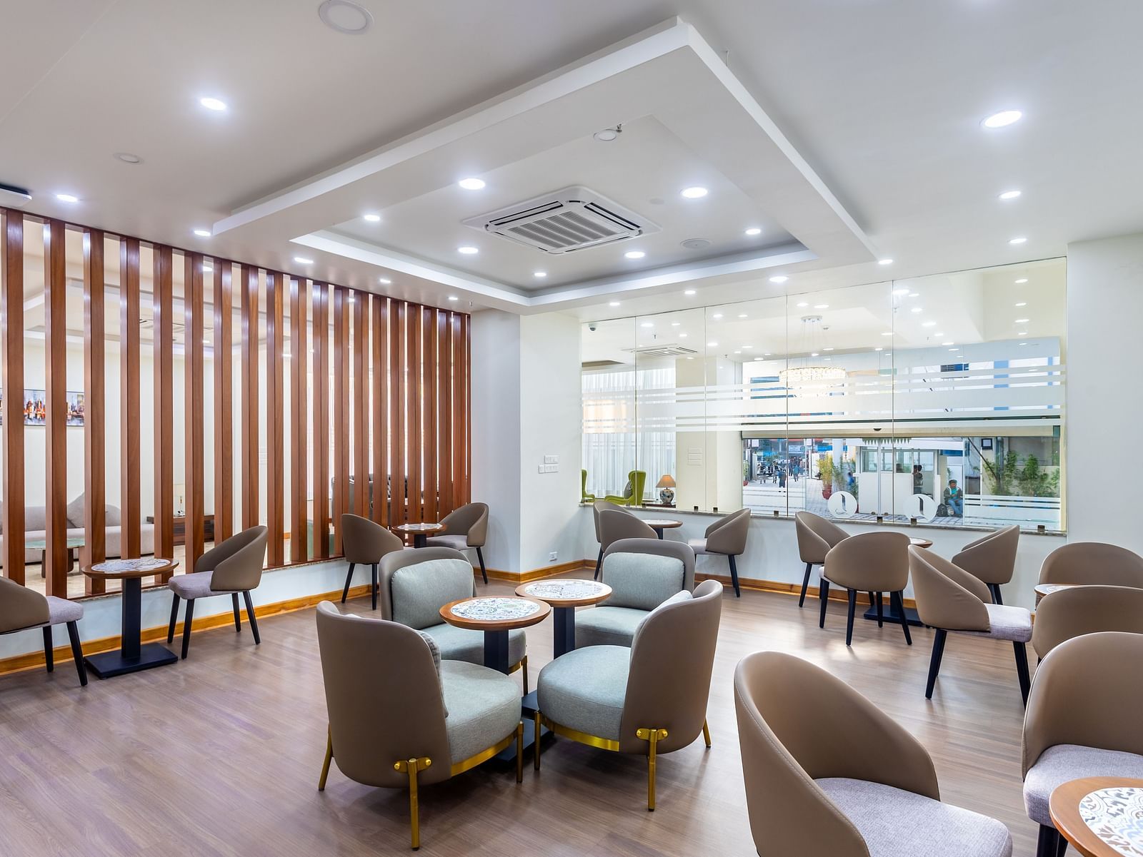 Corner view of the in-house restaurant  that features spacious carpet area and various seating arrangements with a glass-framed wall and overhead lighting at Mandala Norling Lords Prime in Kathmandu.