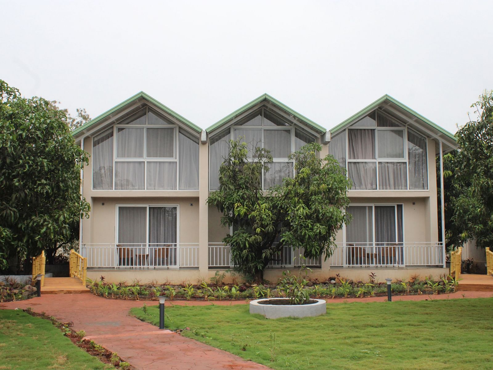 Facade of Mango Leaf Lake Resort, Pune with a garden in front of it