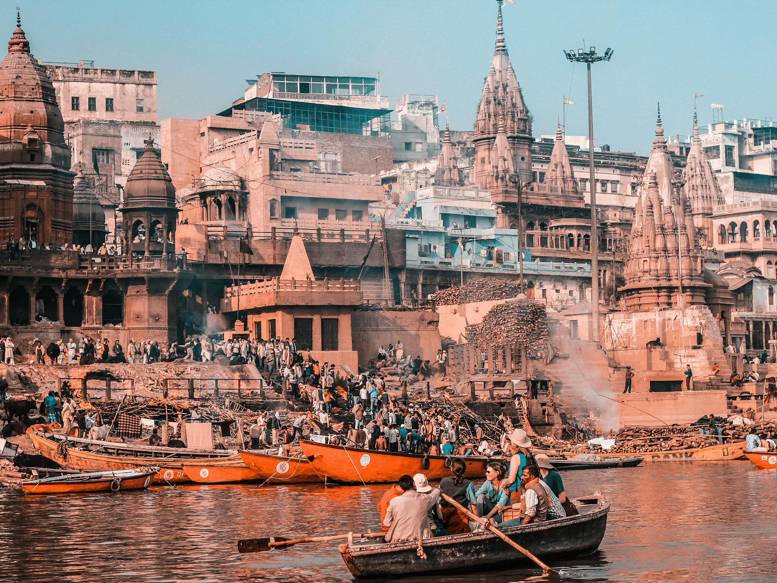 A bustling riverbank scene in Varanasi, India, with ghats and boats.