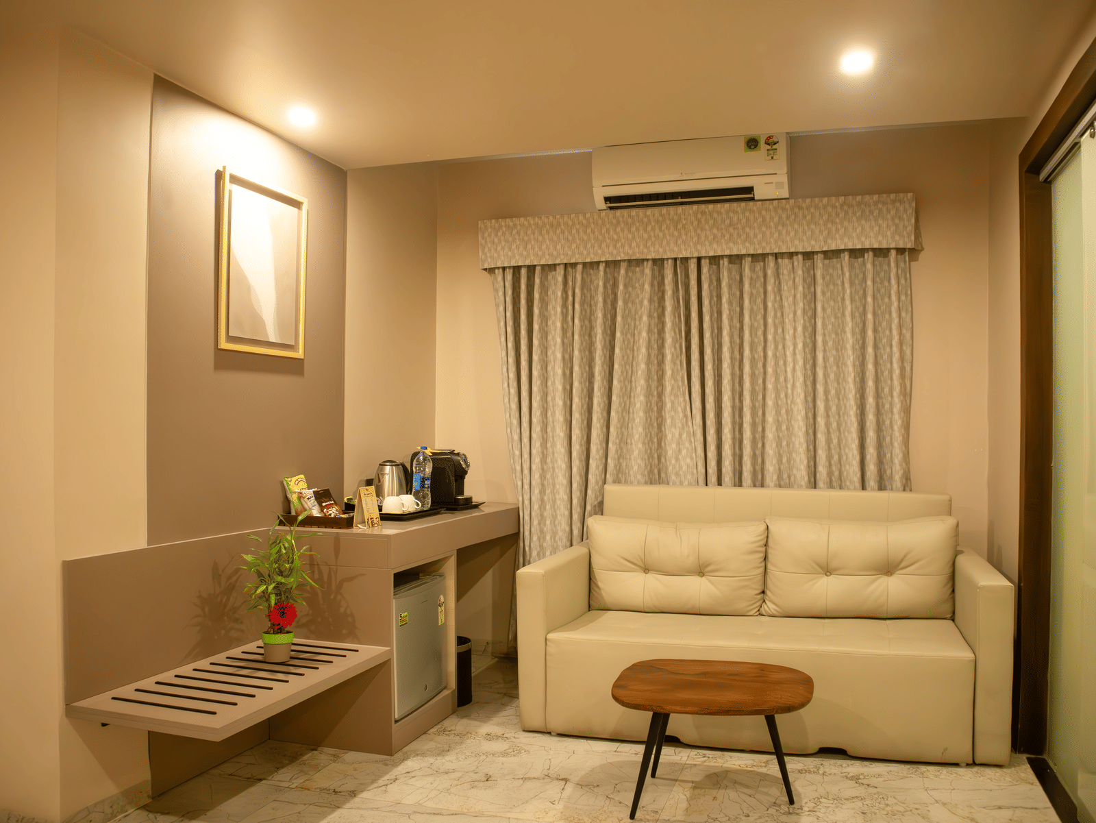 Living room of a Suite at Papaya Tree Hotels having a 2-seating sofa, carpet flooring, a centre table, and large curtains draped over the window.
