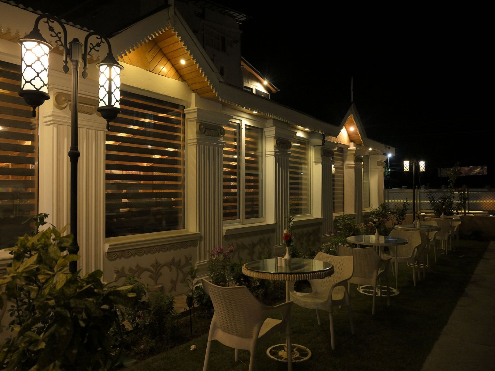 Cosy outdoor seating area at Royal Comfort Regency lit up at night, offering a serene setting for relaxed evening dining.