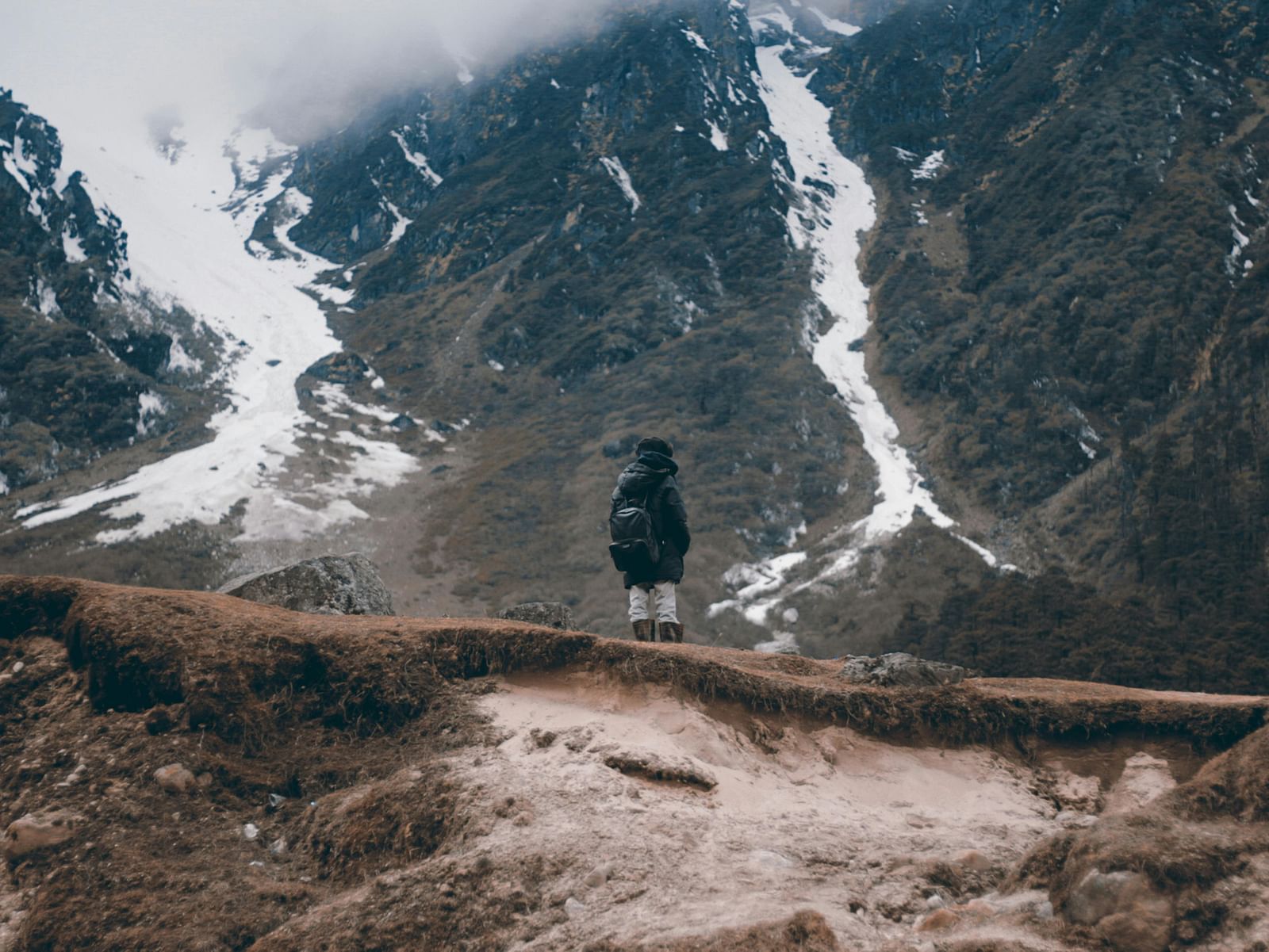 A lone adventurer standing amid rugged, snow-dusted peaks