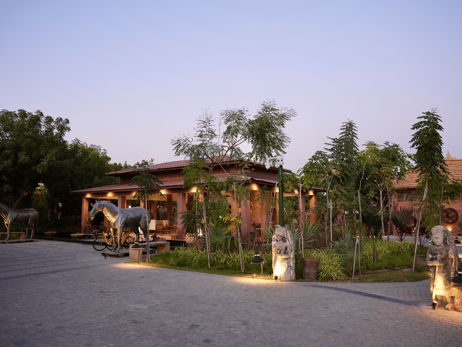 Facade of Surpura Bagh with trees surrounding it and a pathway leading to the reception under evening sky