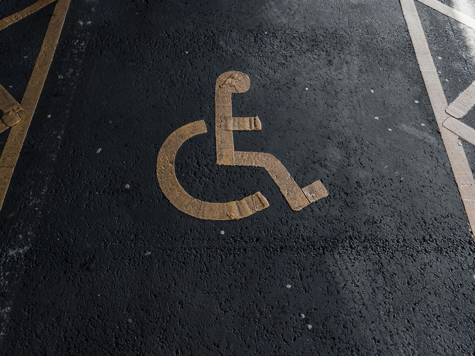 A designated accessible parking space marked with a yellow wheelchair symbol painted on the asphalt.