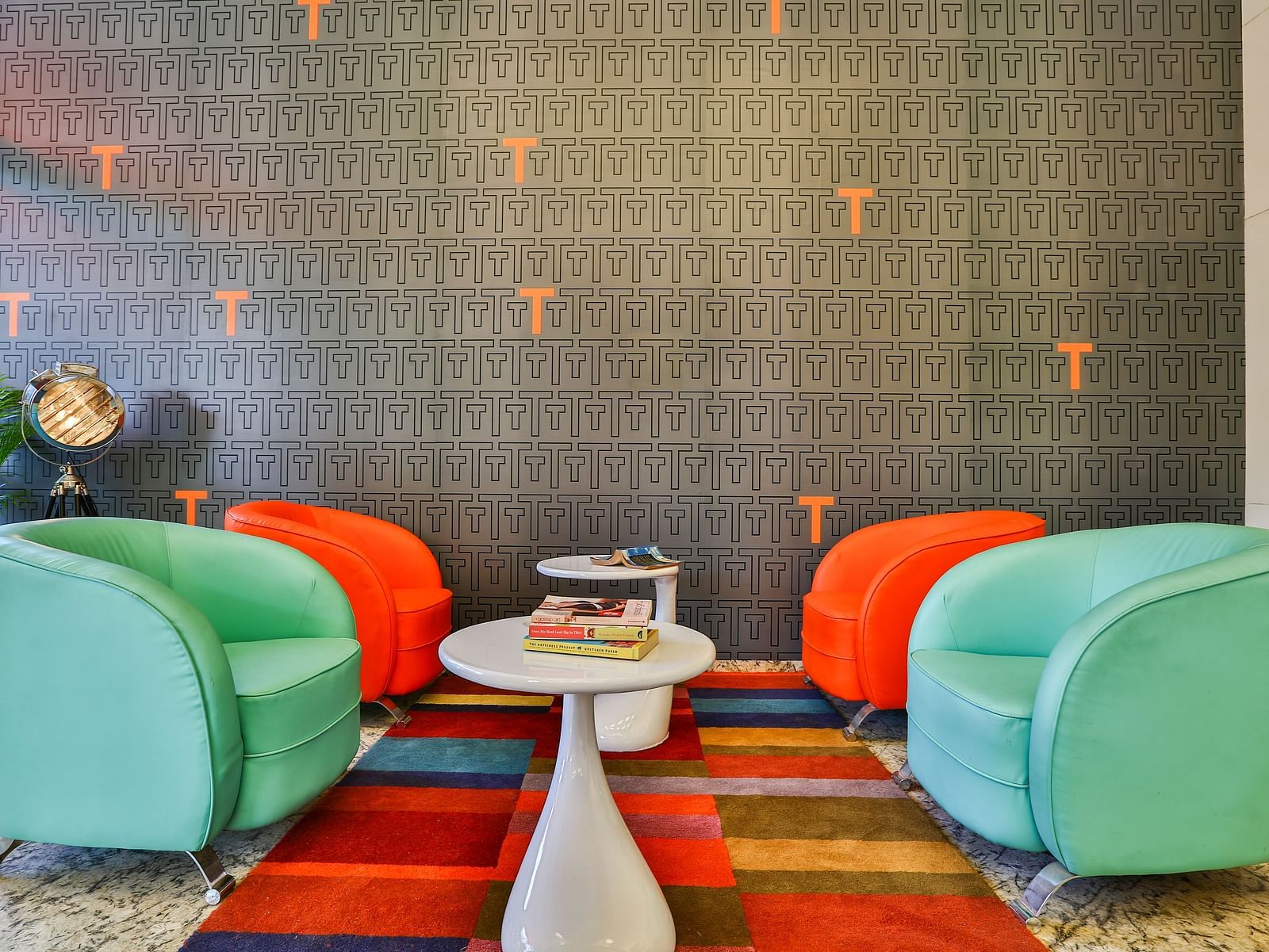 Teal and orange sofa chairs placed on a checked colourful carpet in front on a grey wall at T24 Residency, Andheri East, Mumbai