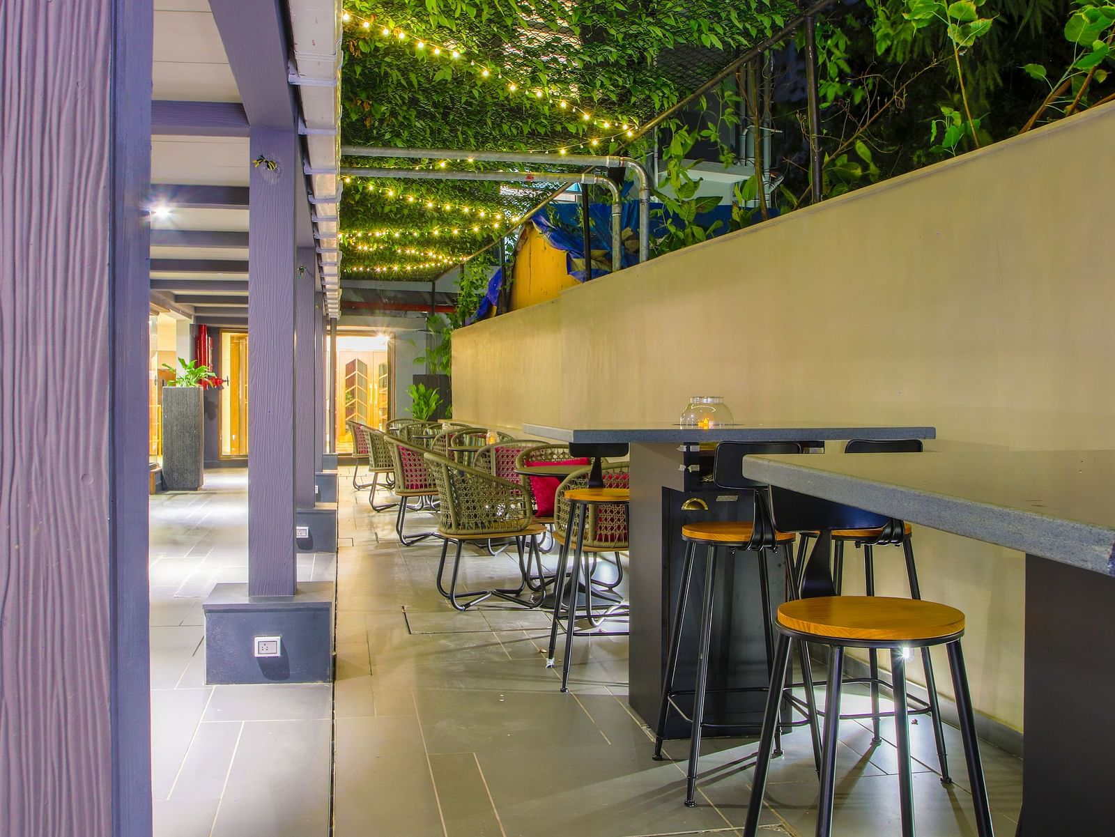 An outdoor dining area with tables and chairs under a wooden pergola  | T24 Retro