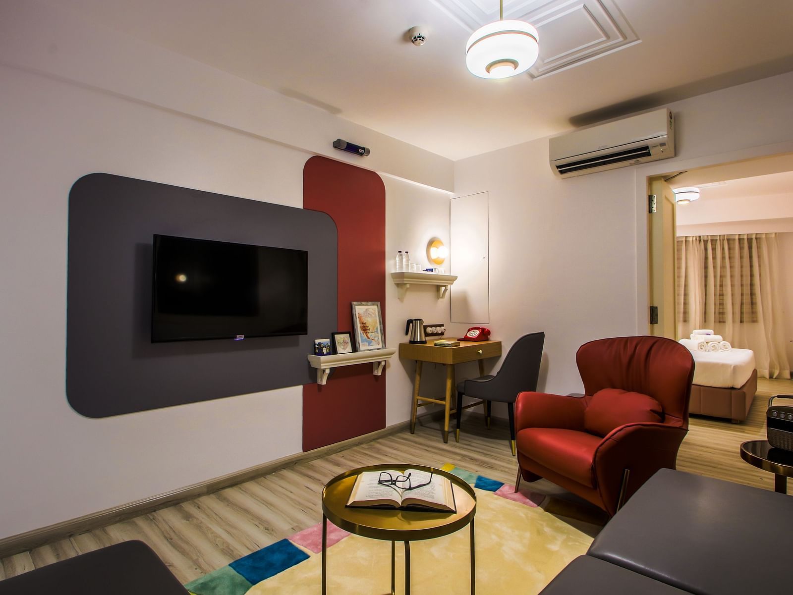 A spacious hotel room with a comfortable seating area, a TV, and a view of another room  | T24 Retro