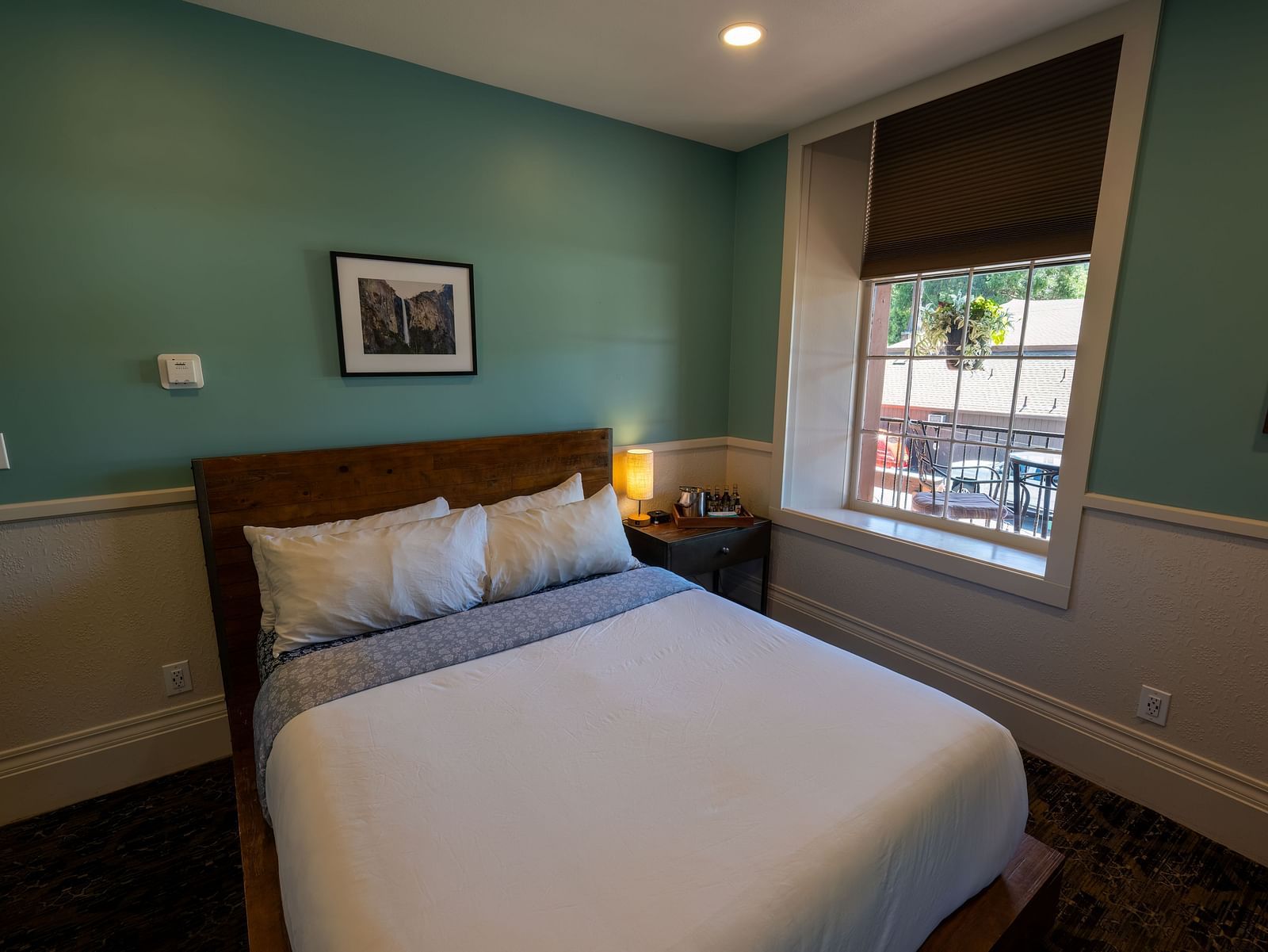 Bright guest room with a double bed and large windows offering natural light at The Groveland Hotel.
