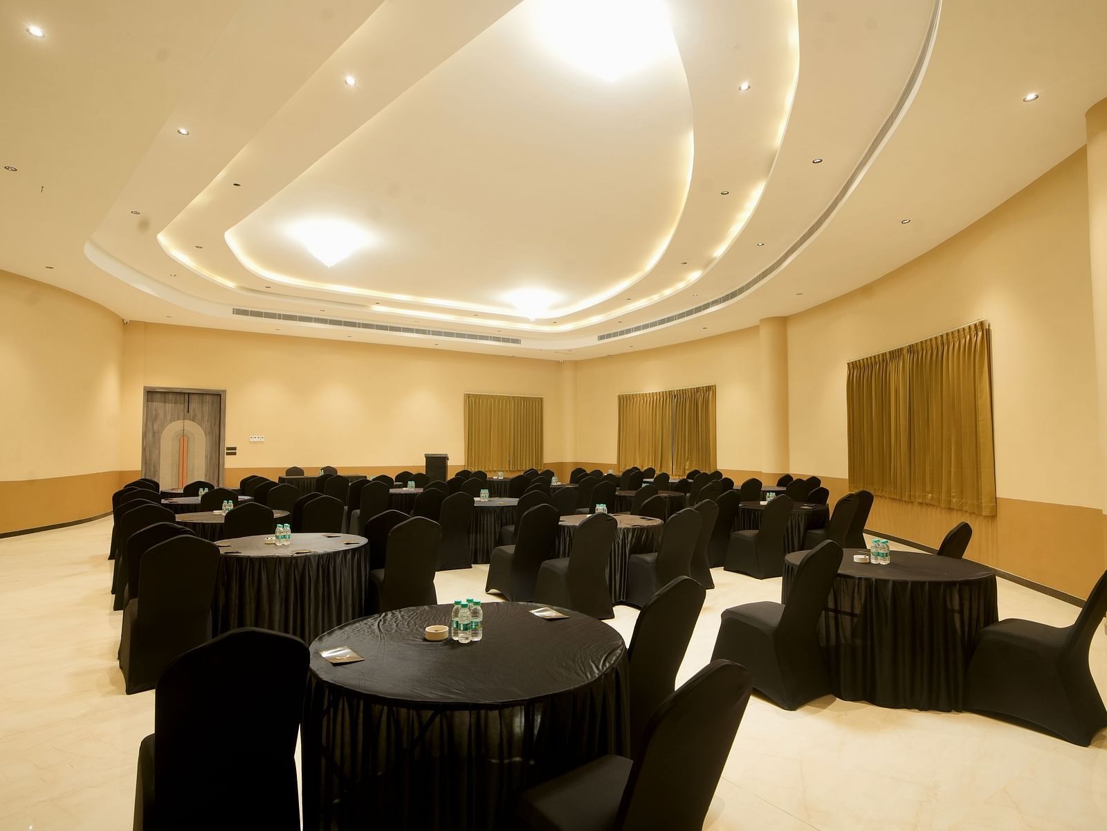 A photo of a hotel ballroom with several tables and chairs set up for an event | Conformance Hall