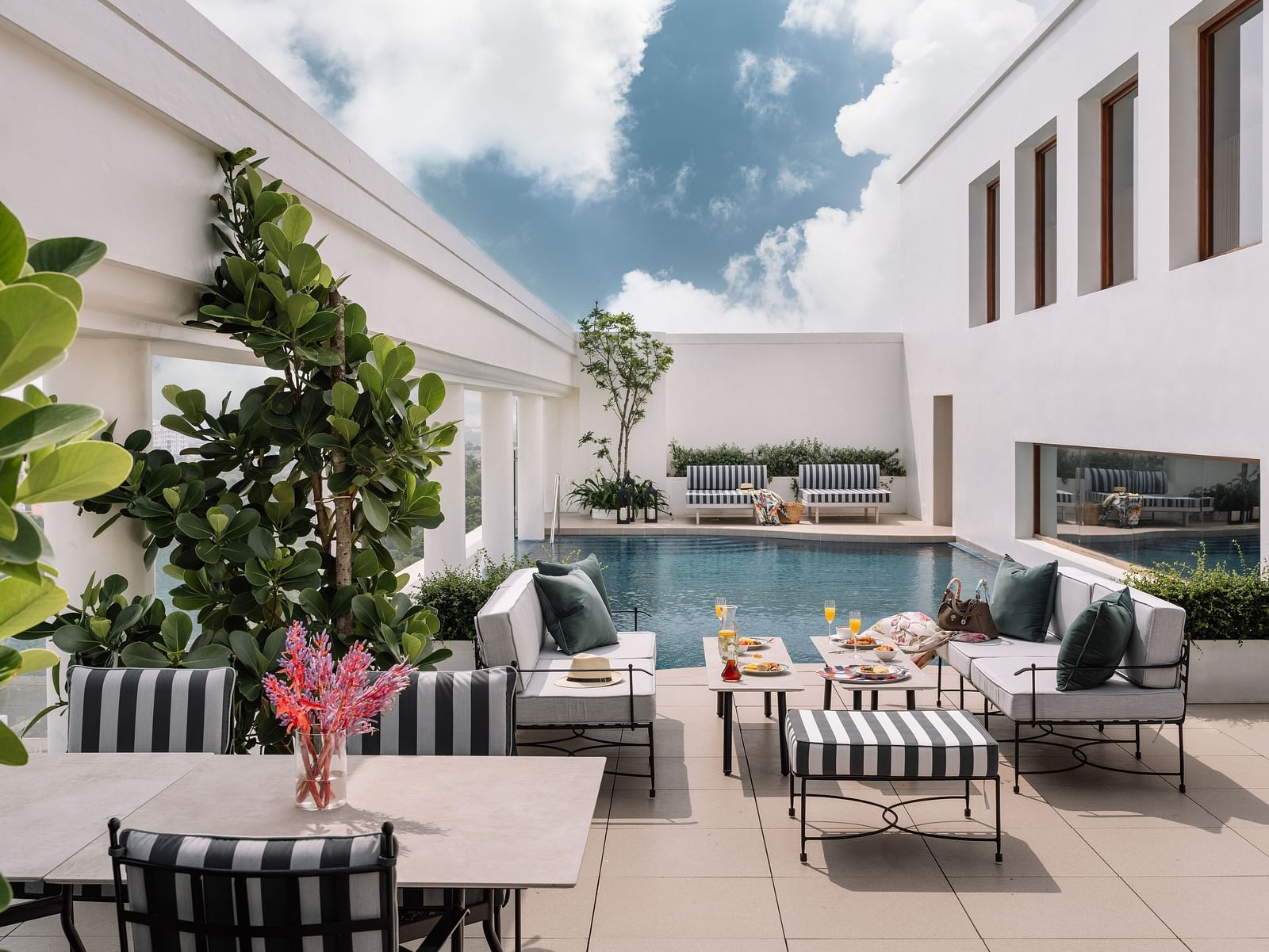An overview of the rooftop swimming pool with loungers, tables and potted plants in view - The Raintree, St. Mary's Road.