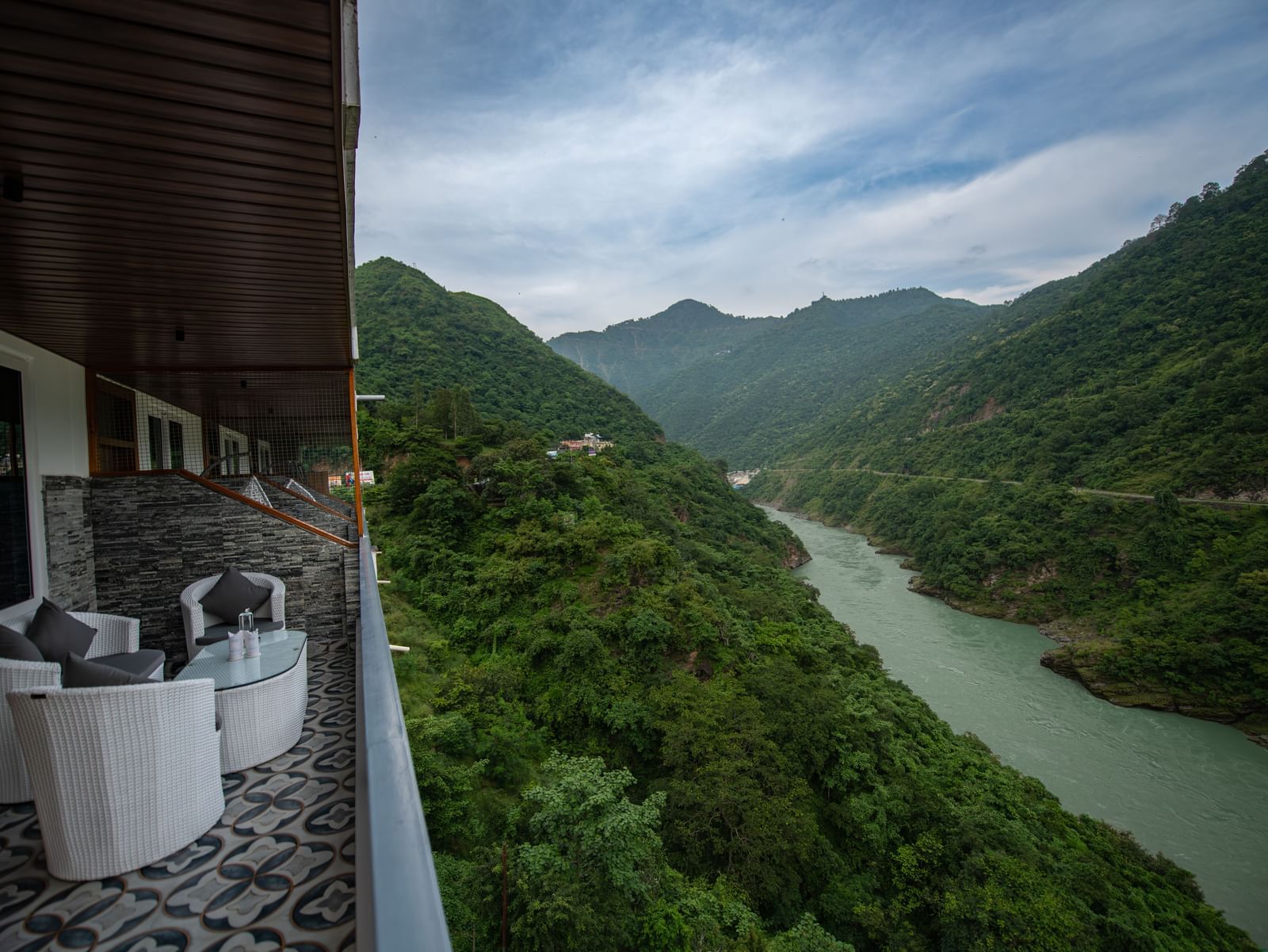 A balcony in the executive room at The Tattva Devaprayag with a view of the mountains and the river.