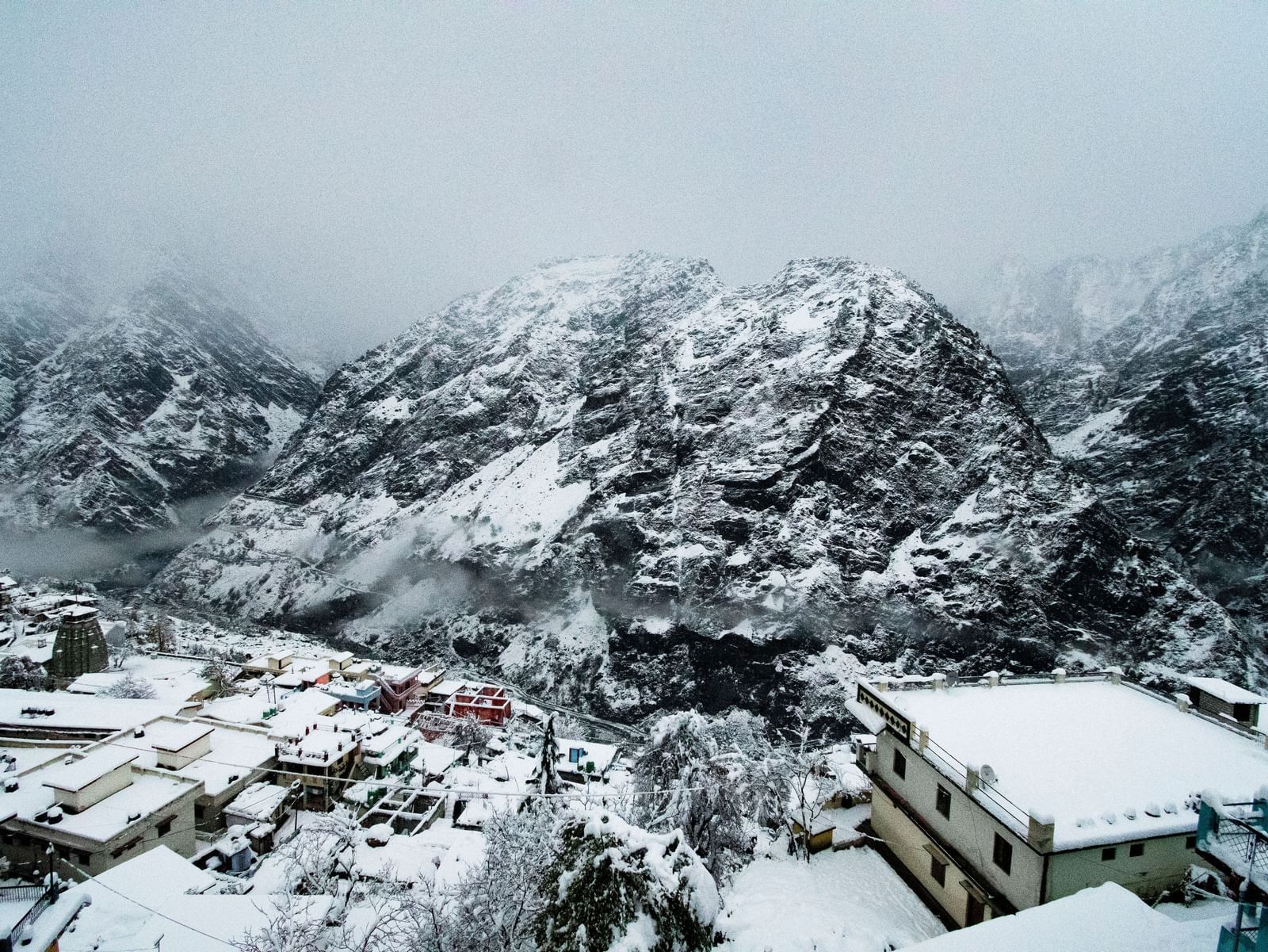 Mountain peaks covered with snow and mist  with small houses in the foothills