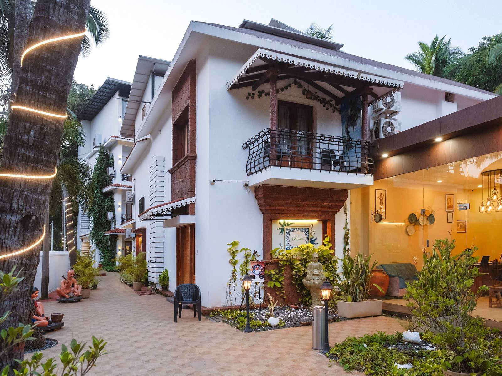 Exterior facade of the resort buildings with a tiled walkway and palm trees at The Verda de Miranda Resort.