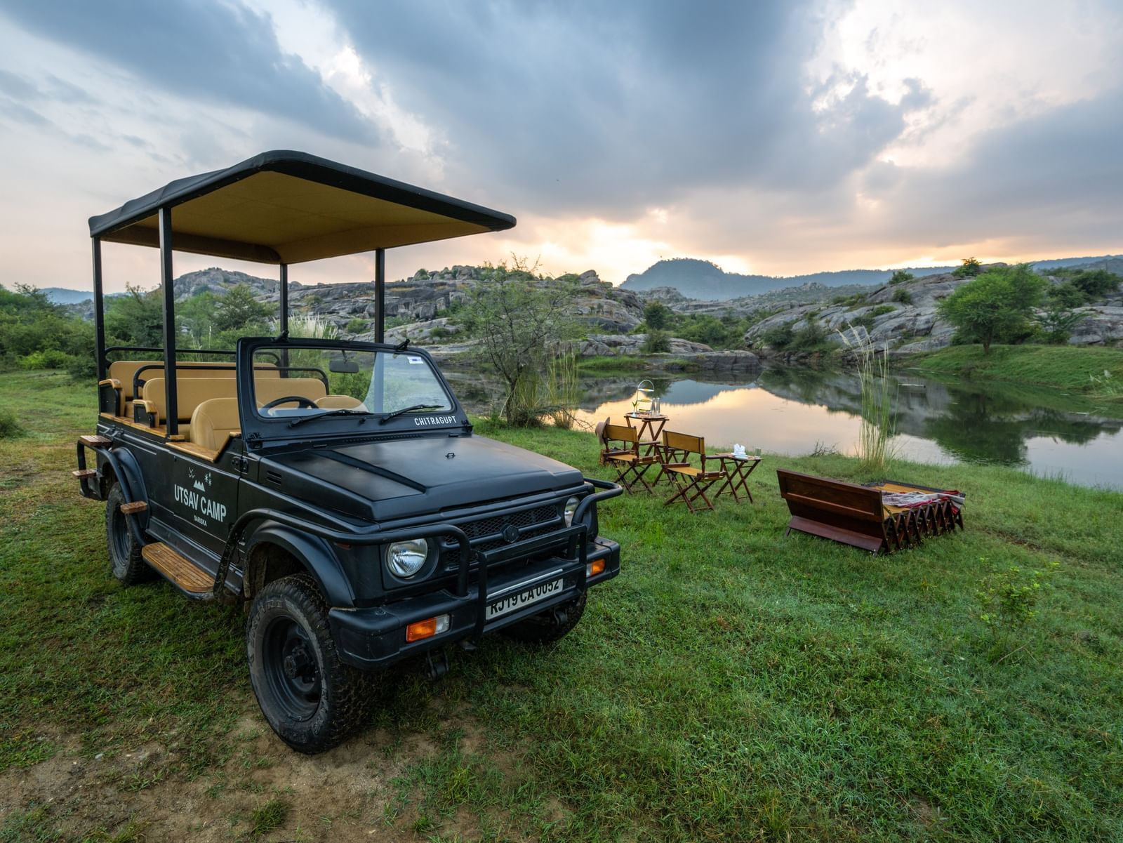 An image of a jeep parked amidst an open field with greenery - Utsav Camp Sariska