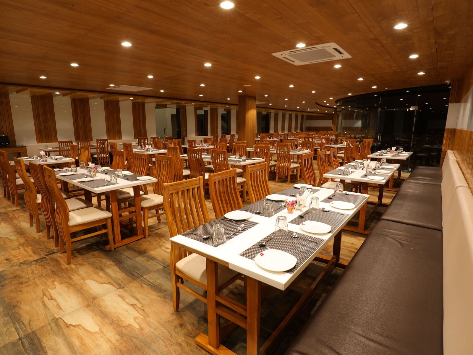 Warmly lit interiors of the Blue Coriander Restaurant with wooden tables and chairs in a cosy atmosphere - Vishal Lords Inn Gir Forest