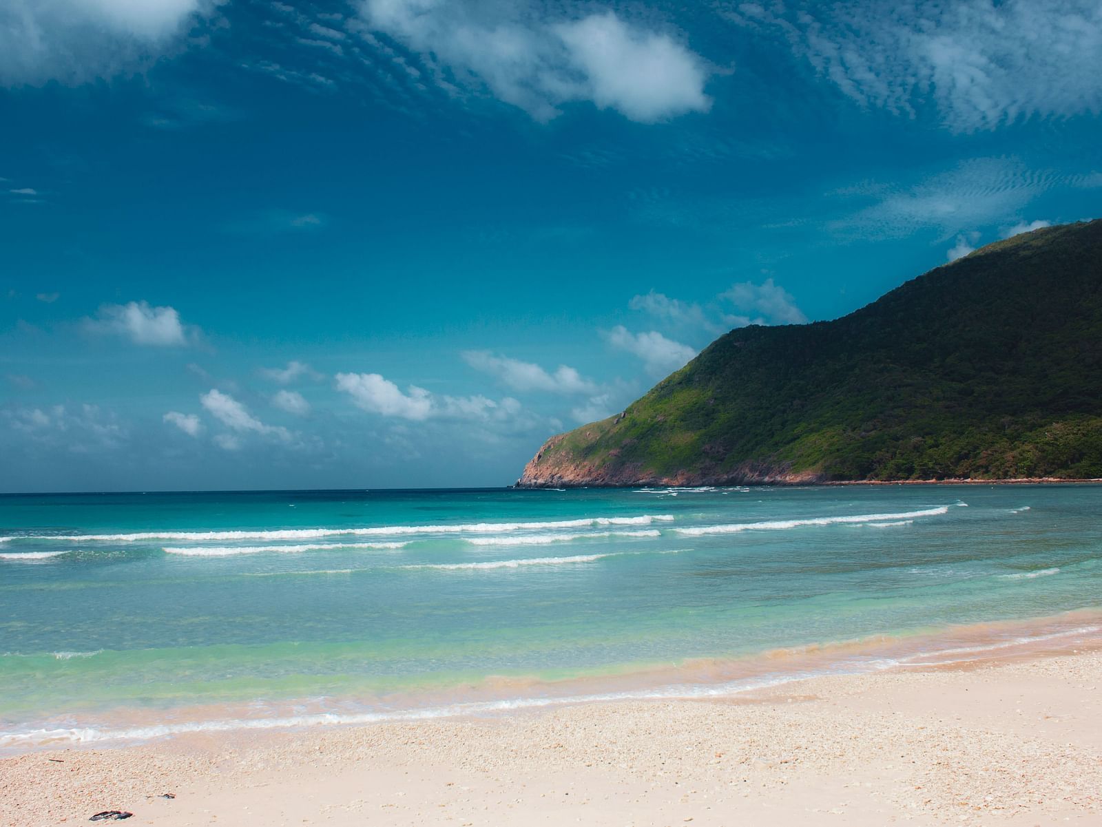 An overview of a beach in Phu Quoc with white sands and a mountain in the background.