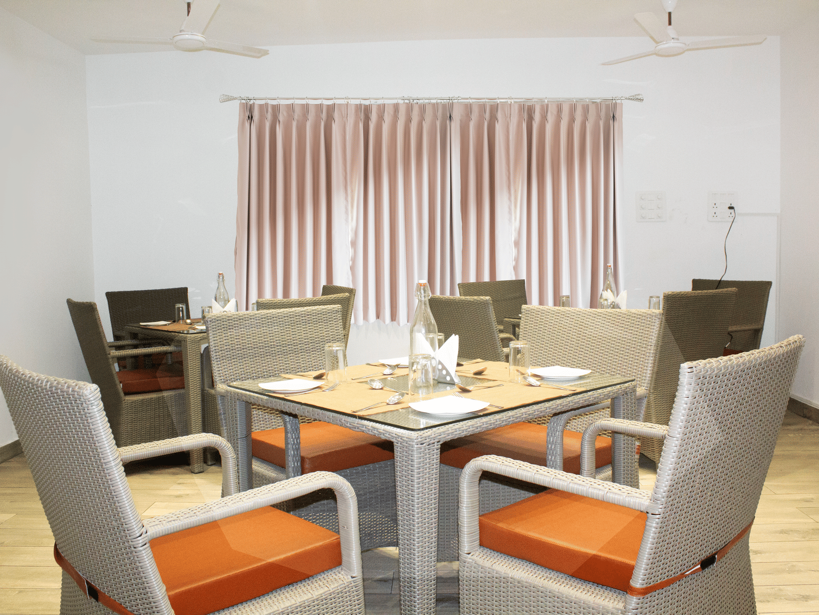 A dining table with orange-coloured cushions on the chair at the Spice and Slice Restaurant at WOW Naturefull Resorts, Yercaud.
