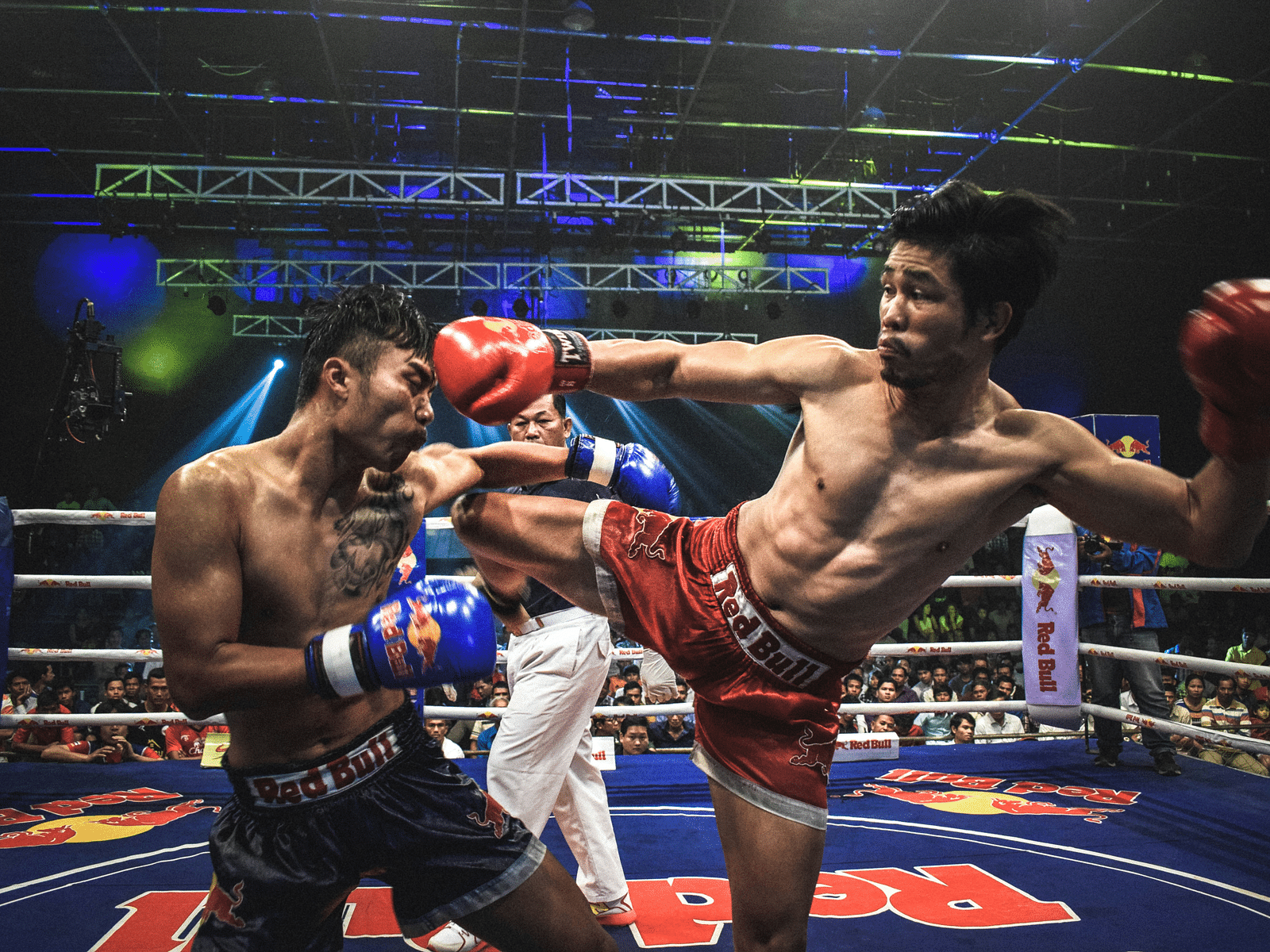 Two players competing in Muay Thai kick boxking in an arena
