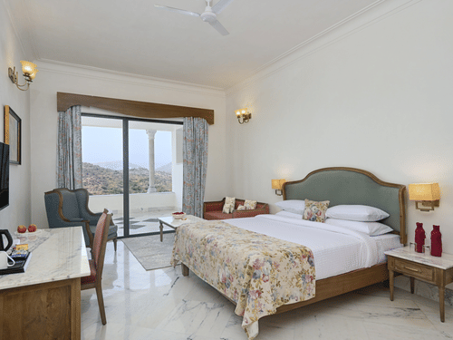Fateh Vilas Udaipur - Interior view of the Family Suite featuring a king size bed a balcony a television and white decor