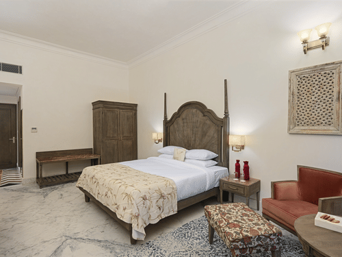 Fateh Vilas Udaipur - interior view of the Renaissance Room featuring a bed a wardrobe a coffee table and white decor