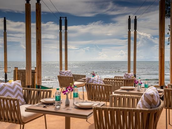 image of well arranged tables and chairs at saz on the beach restaurant with sea waves crashing on the beach in the background
