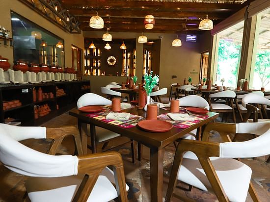 a view of a restaurant with table and plush chairs at Themis Mudhouse - A Nature's Retreat Resort & Wellness