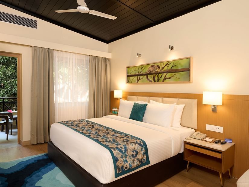 view of a double bed and night stand in the Cottage at ABN Sarovar Portico, Jim Corbett