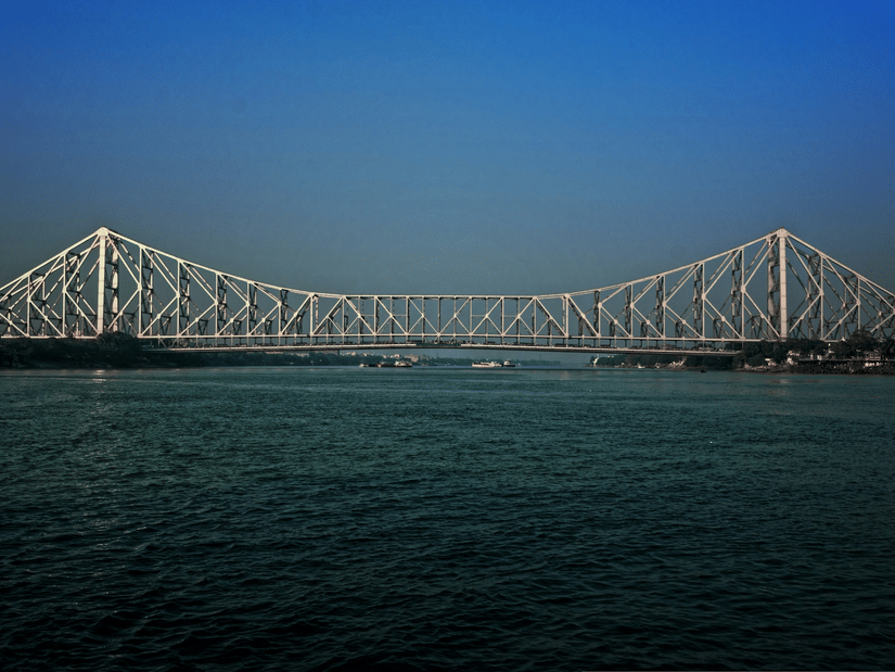 A wide shot of the Howrah Bridge upon the  waters of the Ganges river.