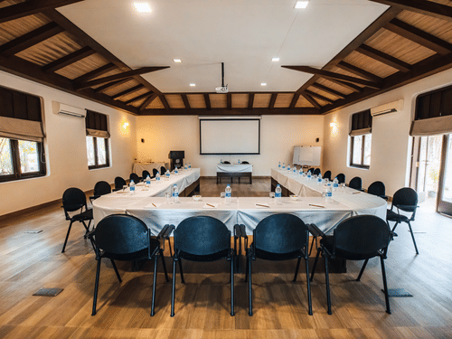 Spacious conference room with long table seating, wooden interiors and modern setup at Jehan Numa Retreat ideal for meetings and corporate gatherings