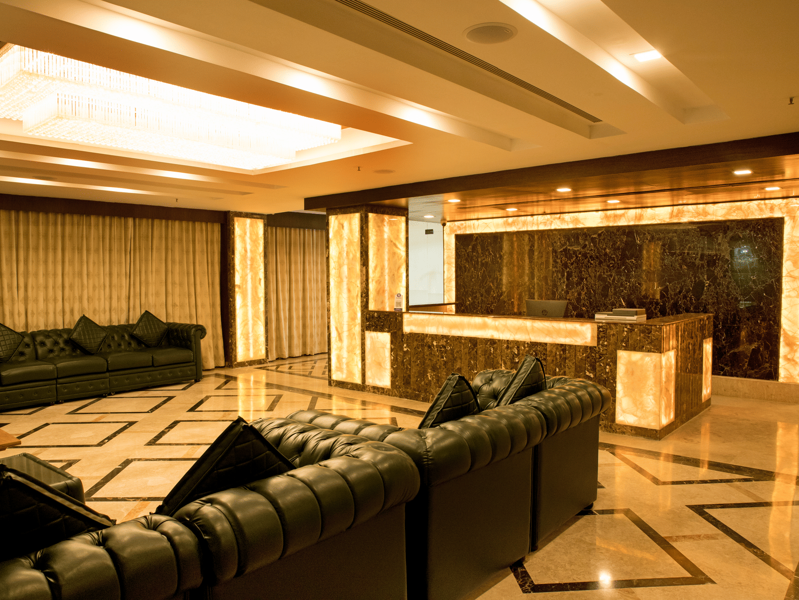 A well-lit hotel lounge at Benzz Park Chennai featuring several comfortable sofas arranged for social gatherings.