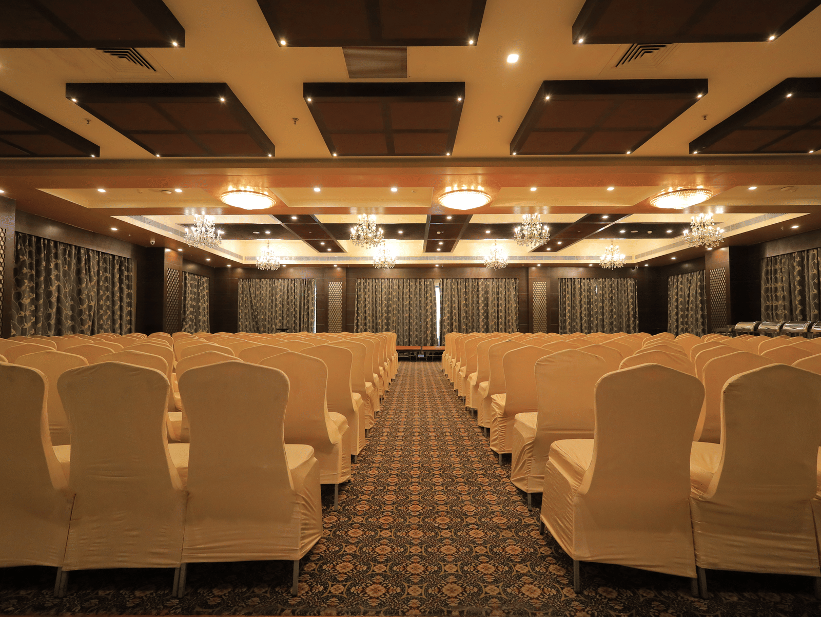 Full view of the Rolse Royse banquet hall with chairs facing towards the stage with a pathway in the middle at Benzz Park, Vellore.