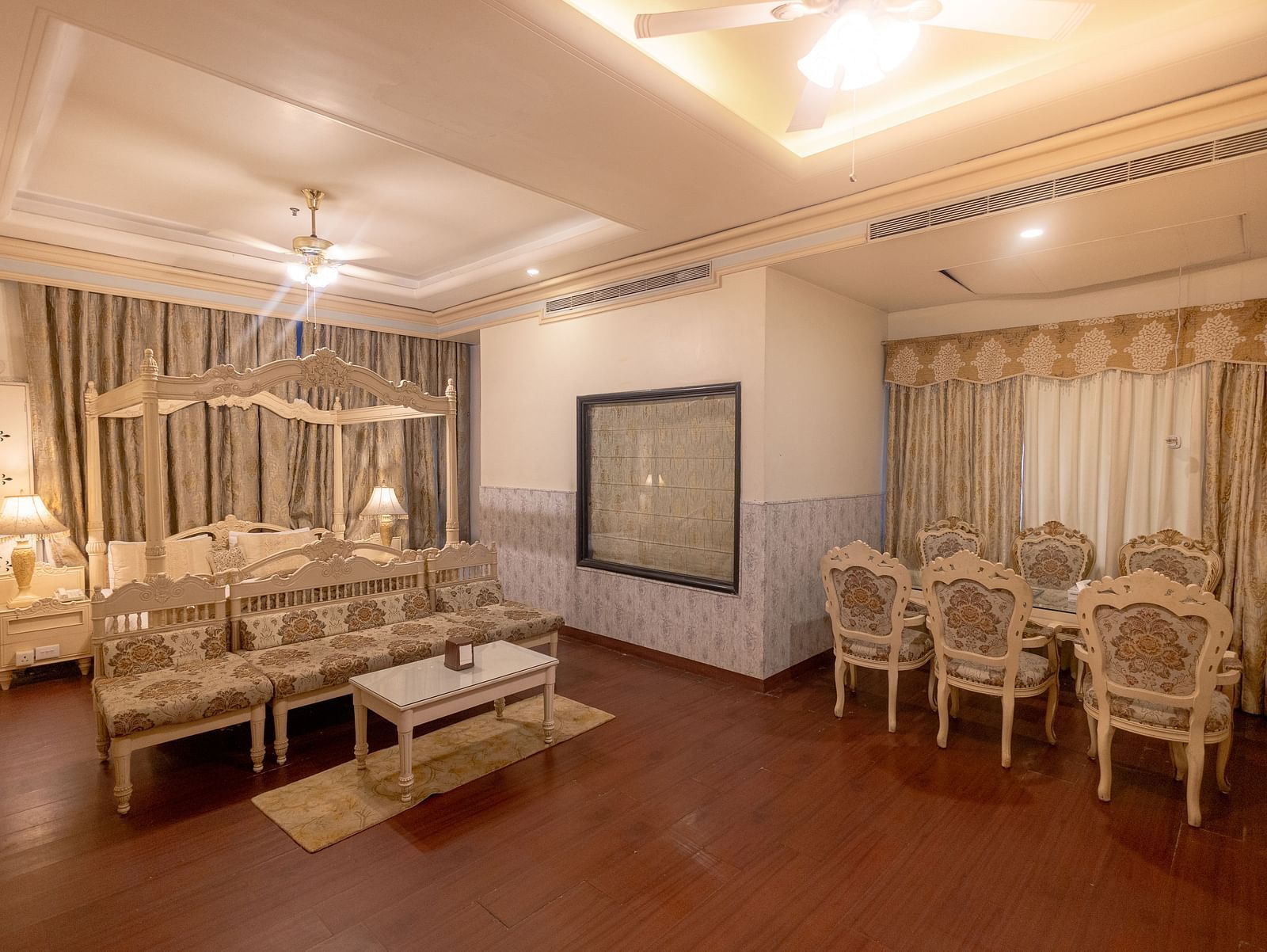 King Suite eaturing a seating area with a sofa and coffee table, a dining area with four chairs, and neutral-toned decor.- Hotel Ashok Nagpur