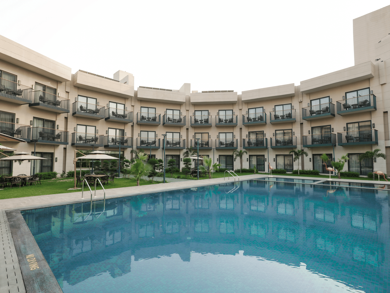 Poolside view of the hotel's courtyard and room balconies at Ramada by Wyndham Sonipat Murthal