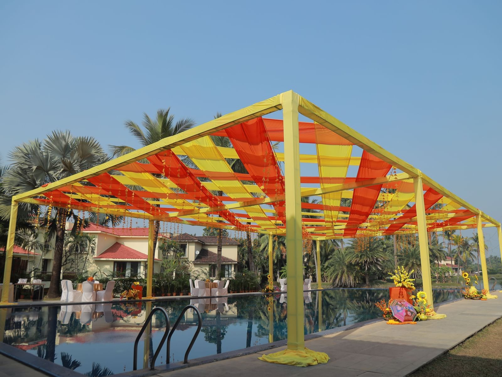 A pool side event space at Vedic Village Spa Resort featuring a  colourful shamiana.