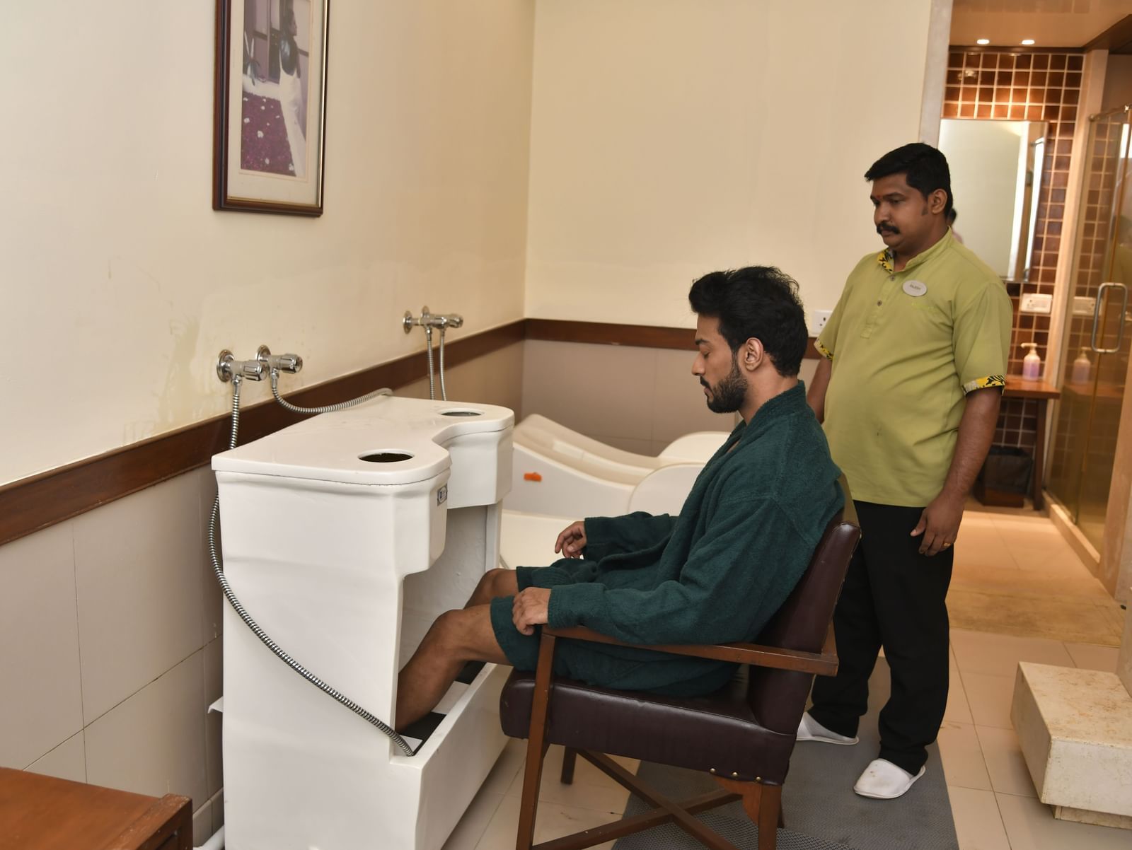 Guest seated for a therapeutic foot or leg detox bath under the supervision of a spa therapist.