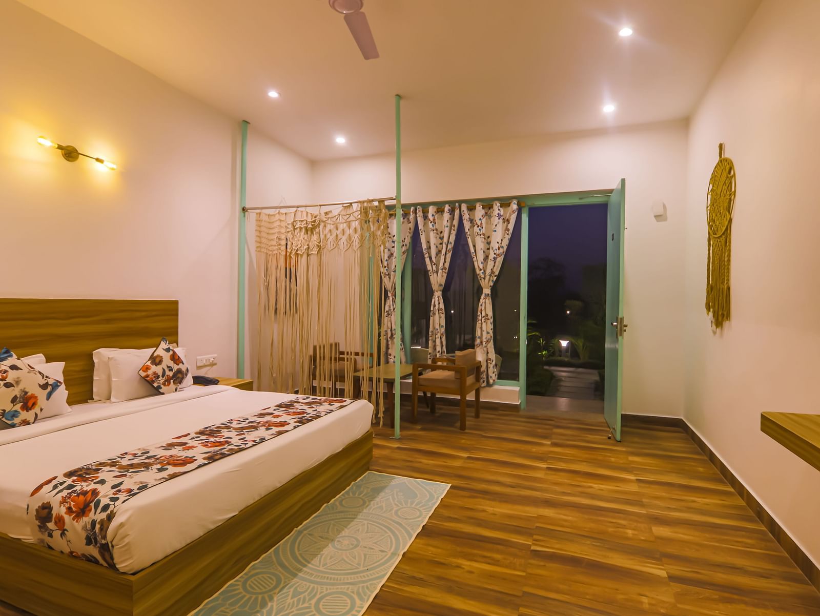 A well-lit bedroom at Vedikant Resorts The Mallard Corbett features a bed, seating area, and open balcony doors.