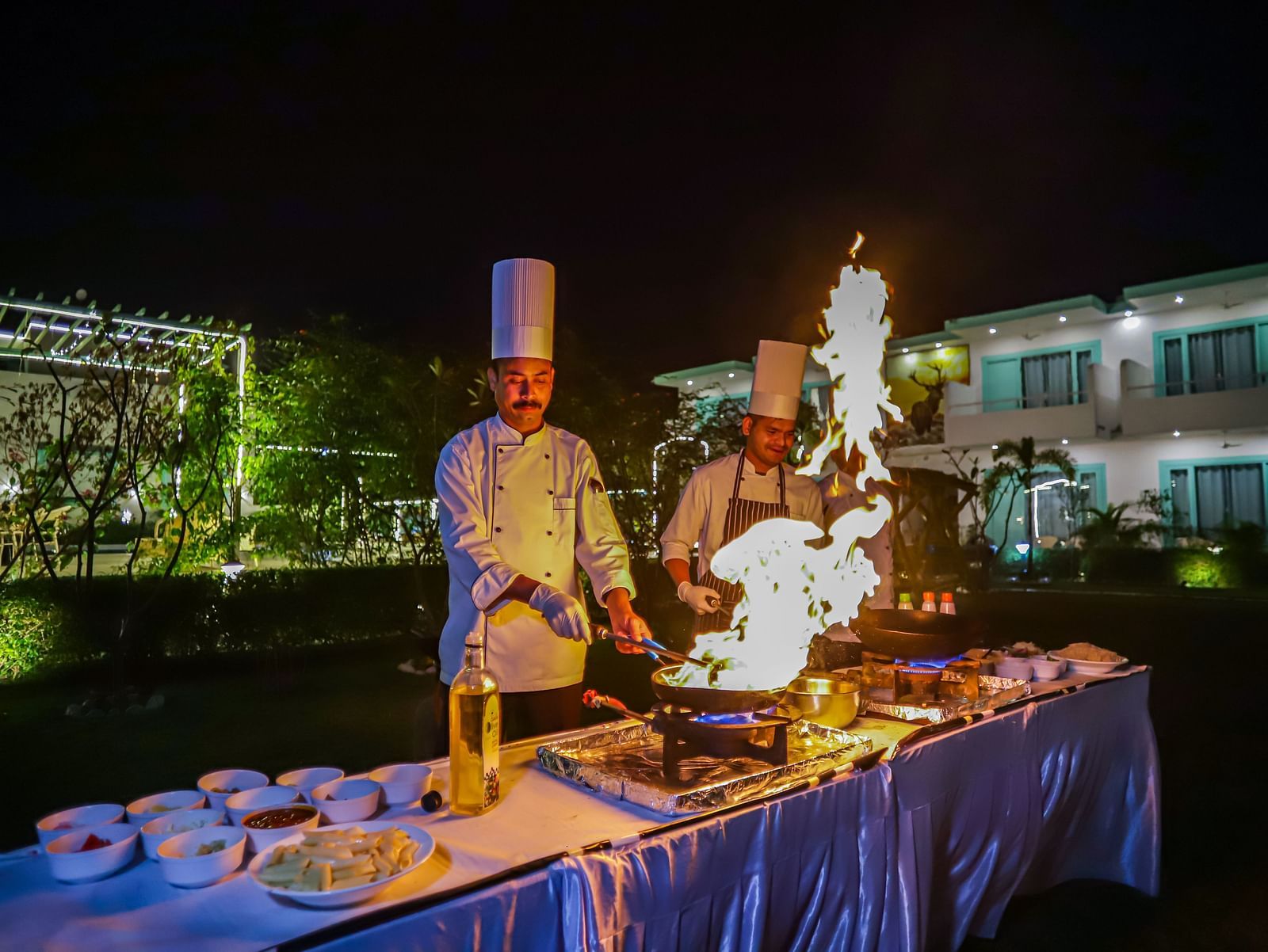 Buffet setup with chefs preparing fresh food during a nighttime live cooking event at Vedikant Resorts The Mallard Corbett.